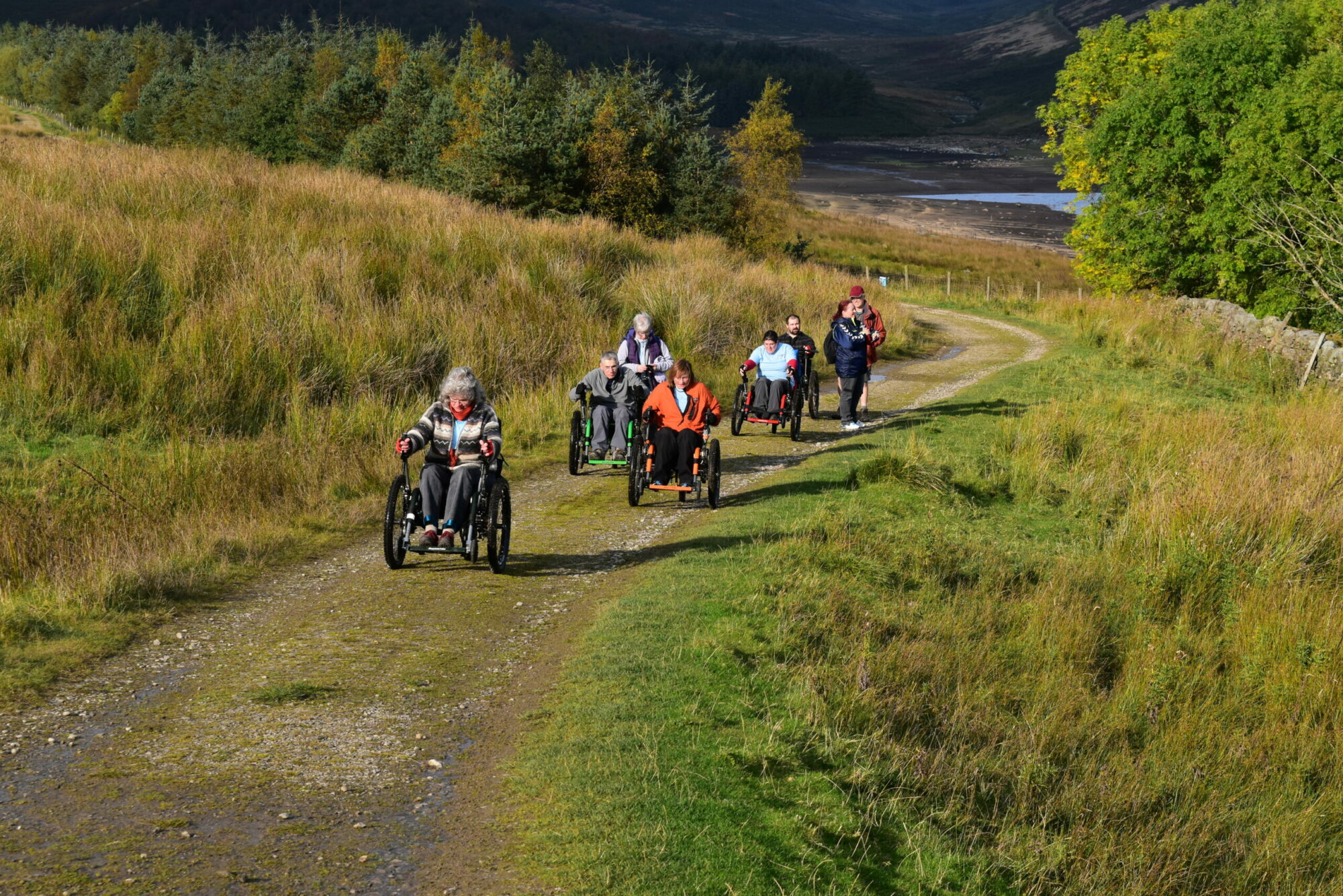 Inclusive Walks with Experience Community Post image 3 A group of people using Mountain Trike All-Terrain Wheelchairs at Yorkshire Water's Grimwith Reservoir.