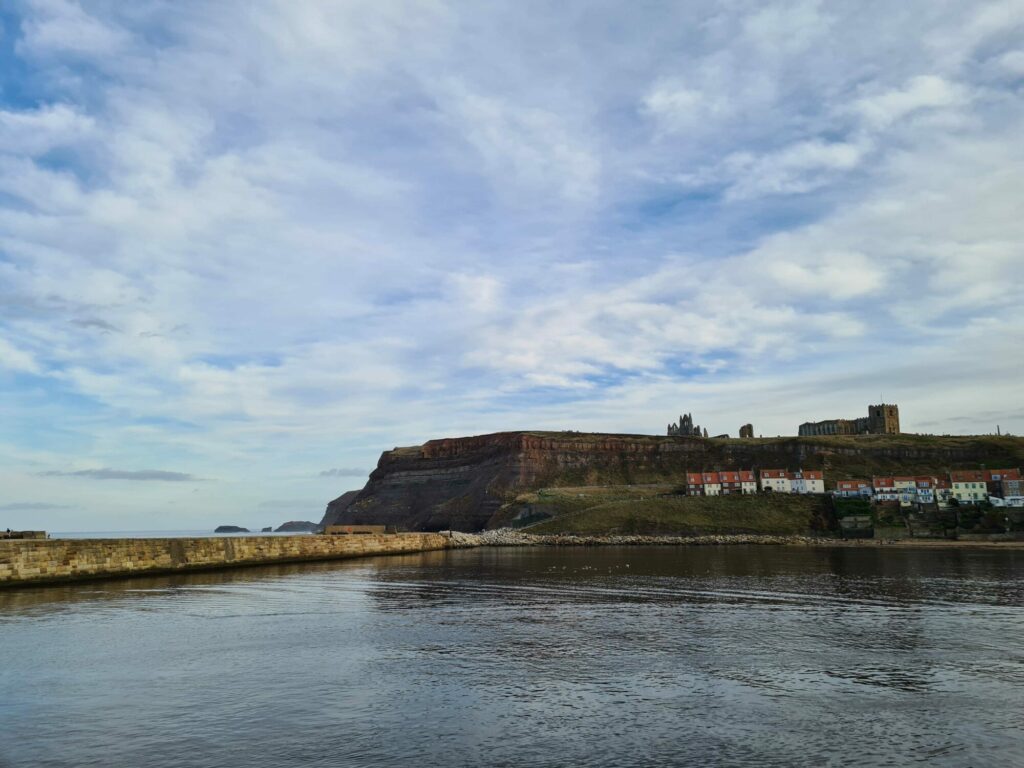 Image name whitby harbour and and cliffs calm sea copyright yorkshire com international ltd the 16 image from the post Whitby in Yorkshire.com.