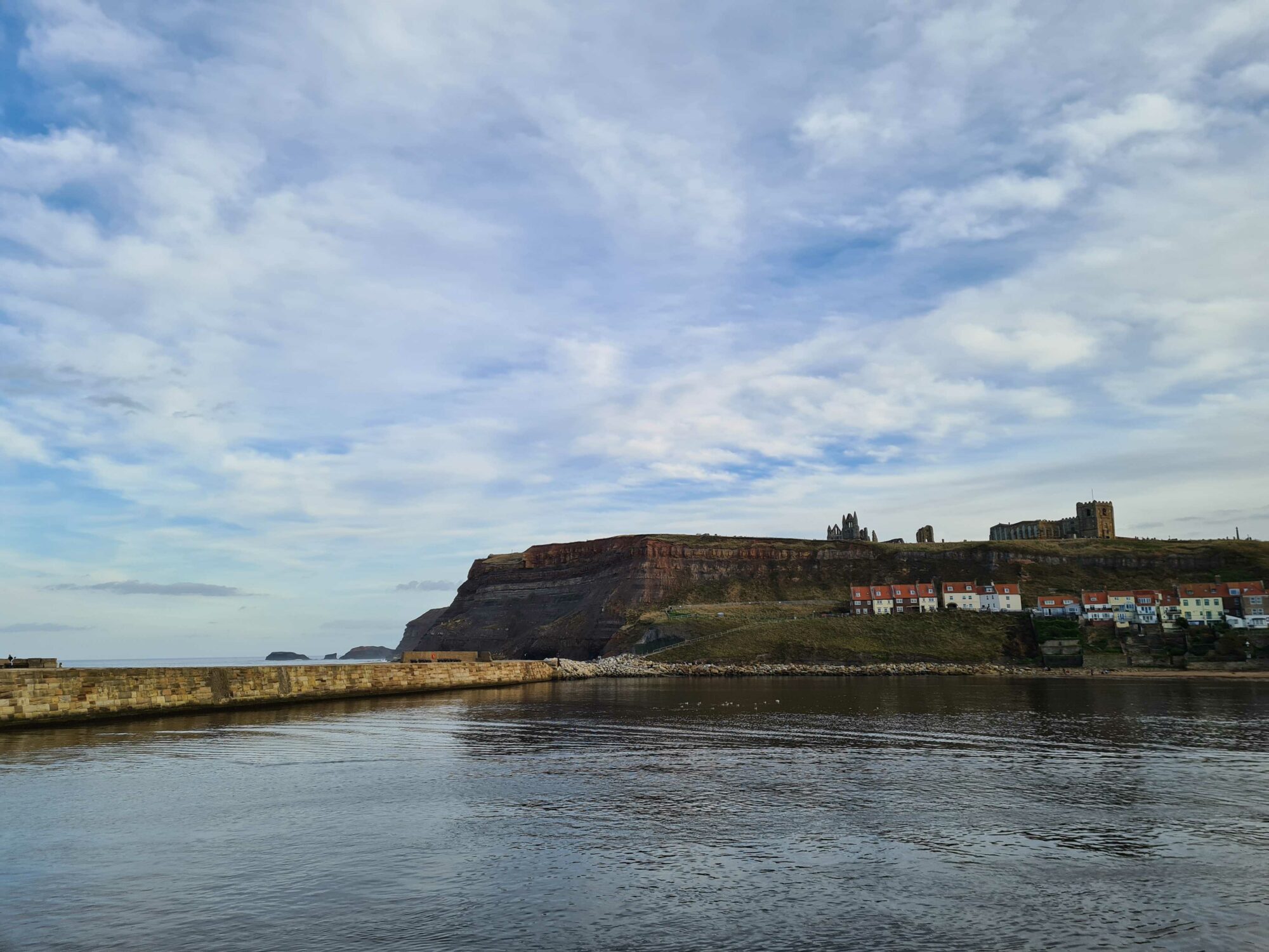 Looking Forward to Spring Bank Holiday in Yorkshire: Top Places to Visit and Where to Stay Post image 3 Image name whitby harbour and and cliffs calm sea copyright yorkshire com international ltd the 3 image from the post Looking Forward to Spring Bank Holiday in Yorkshire: Top Places to Visit and Where to Stay in Yorkshire.com.