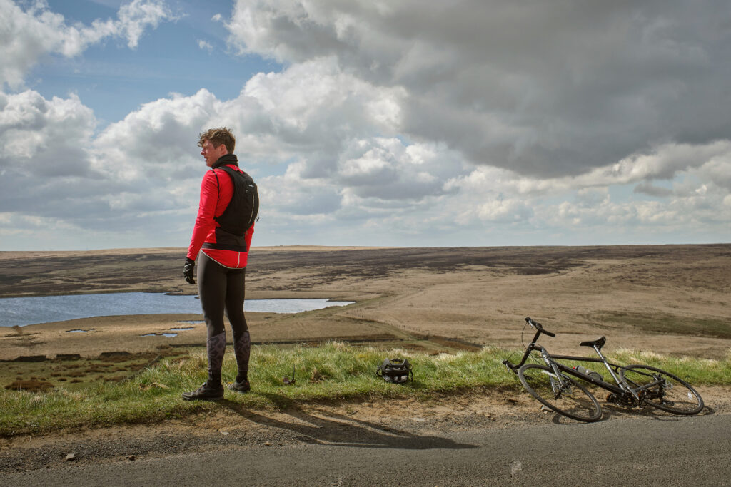 Where Happy Valley is filmed in Yorkshire - locations, venues and studios Post image 5 James Norton as Tommy Lee Royce in Happy Valley 3, cycling outfit above Warley Moor reservoir with bike