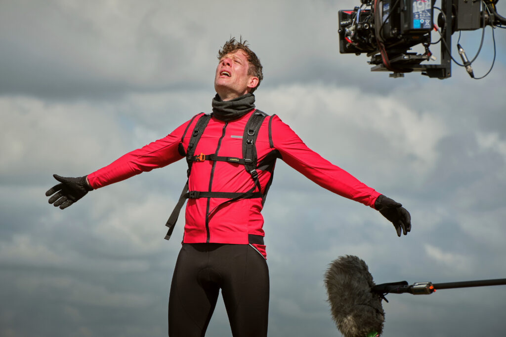 Where Happy Valley is filmed in Yorkshire - locations, venues and studios Post image 6 James Norton as Tommy Lee Royce in Happy Valley 3, filming behind the scenes in cycling outfit above Warley Moor reservoir with bike