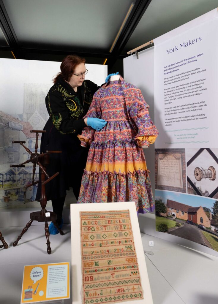 Discover the Secrets of Dress at York Castle Museum’s Refreshed Fashion Gallery Post image 1 Image name Secrets of Dress 4 Dr Faye M Prior Curator of Social History with a Droopy Browns dress see full credit listing ©Duncan Lomax Ravage Productions 1 the 1 image from the post Discover the Secrets of Dress at York Castle Museum’s Refreshed Fashion Gallery in Yorkshire.com.