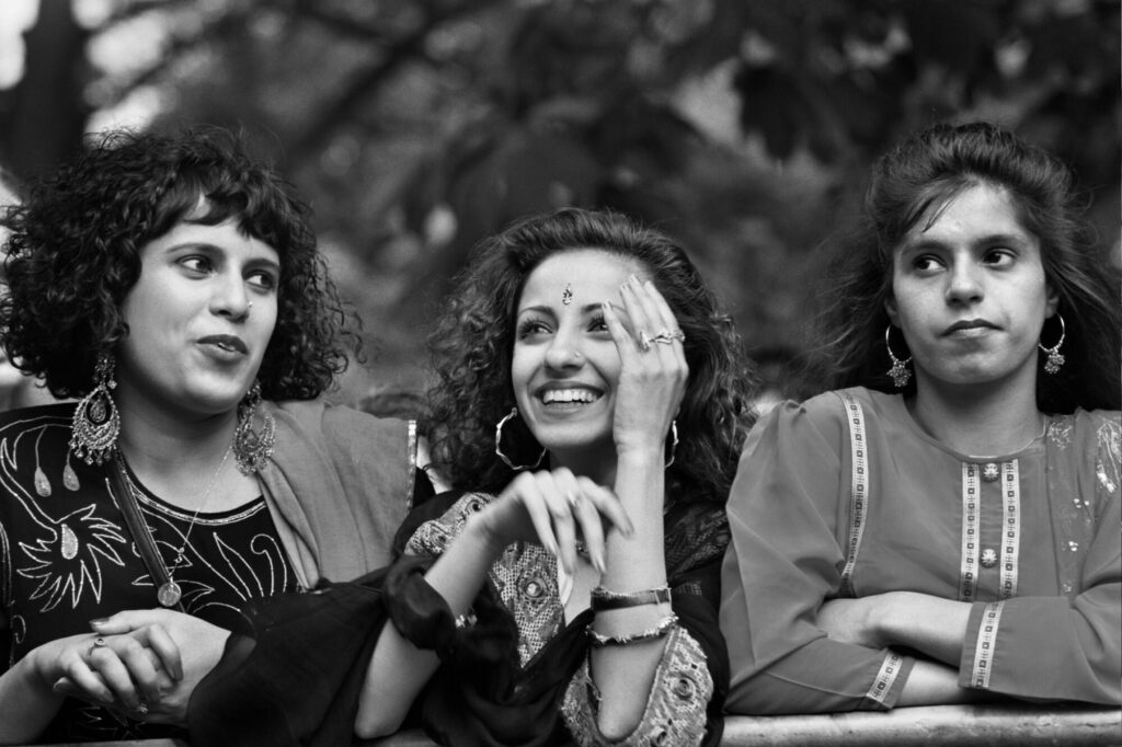 Image name 26403 Women enjoying the Bradford Mela. Late 1980s. Photo by Tim Smith early 16A 0222 BW Tim Smith 1 the 1 image from the post Bradford 2025: What Were The Secret Daytimer Parties For South Asian Youth In The 1980s? in Yorkshire.com.